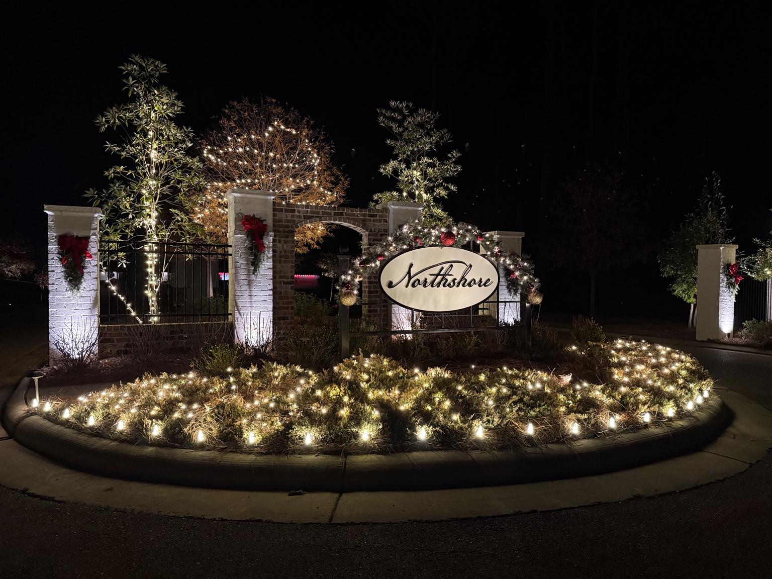 Decorated neighborhood entrance with warm white holiday lights