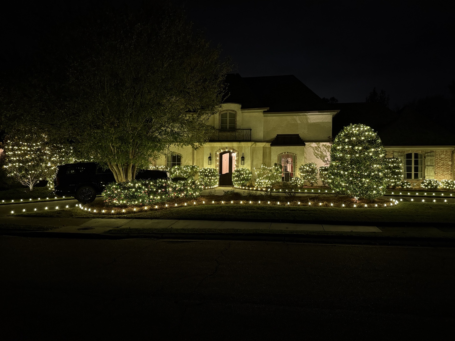 Large home with shrubs and landscape Christmas lighting