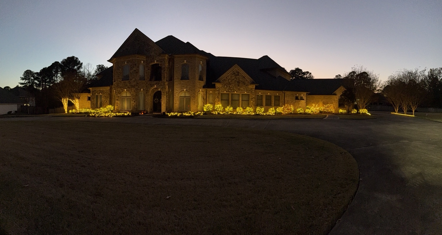 Large residential landscape display with warm white Christmas lights