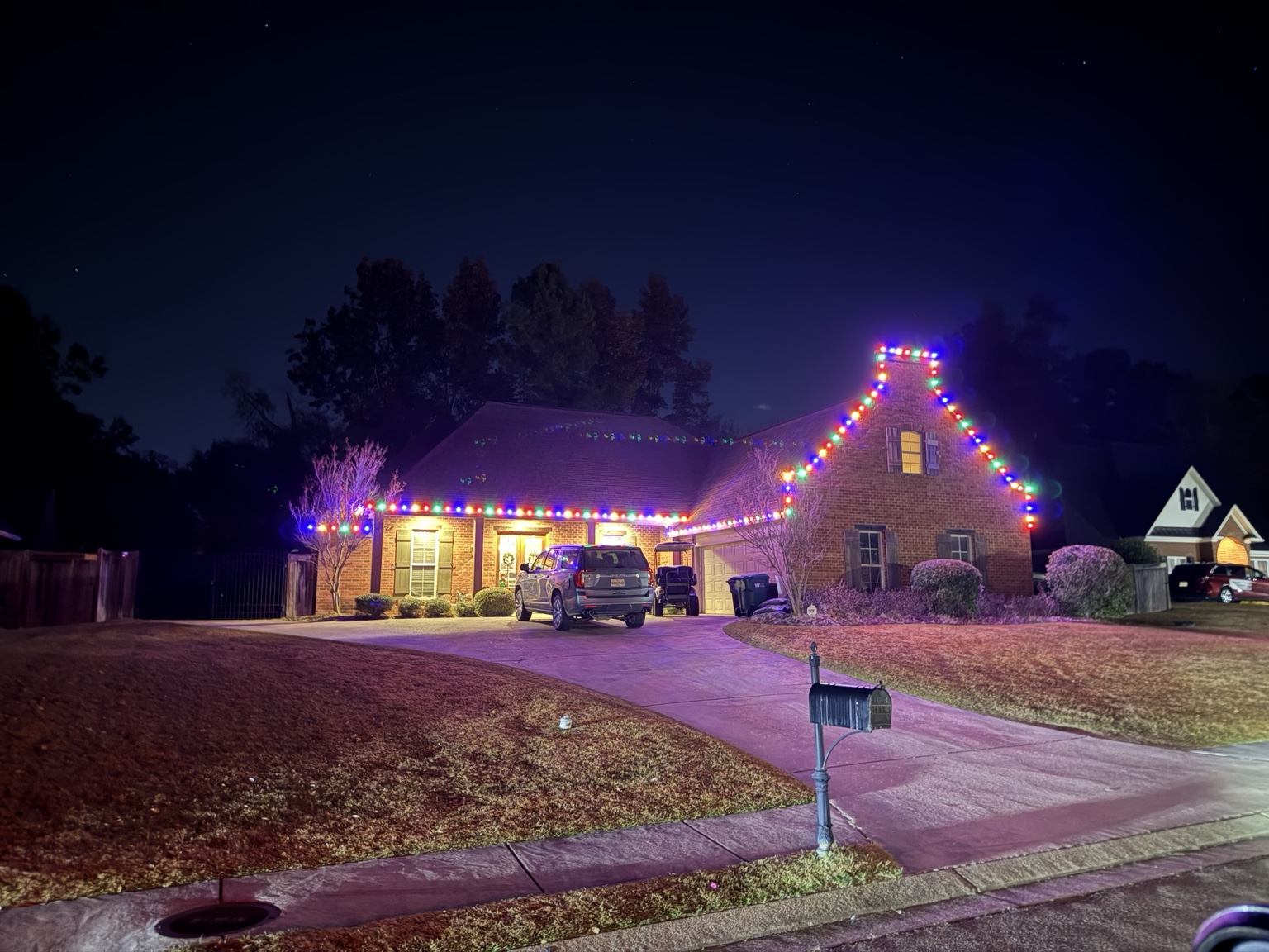 Multicolor Christmas roofline lighting on a brick home
