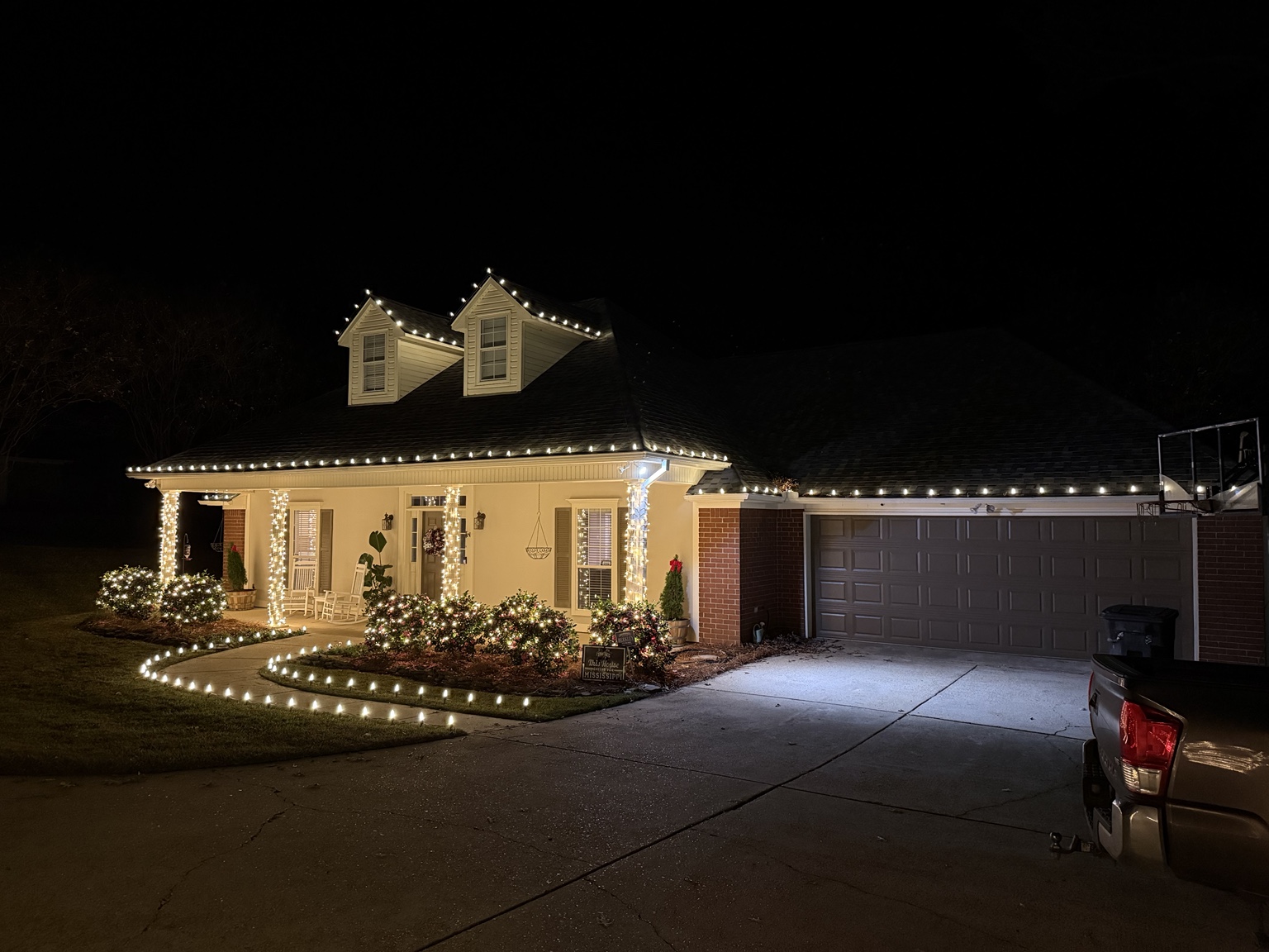 Christmas lights outlining a roofline, columns, shrubs and walkway